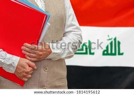 Woman holding red folder on Iraq flag background. Education and jurisprudence concept in Iraq