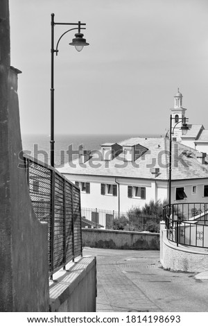 Downhill street leading to the sea in Boccadasse district in Genoa, Italy. Black and white urban photography