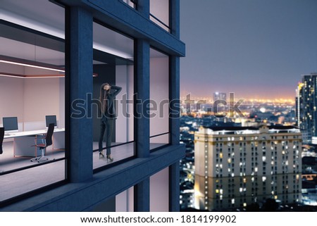 Young businesswoman standing in office and looking on night city. Ñareer and challenge concept