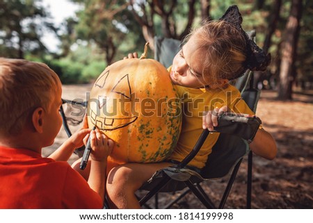 Alternative safe celebration. Cute kids preparing Halloween party in the trunk of car with carved pumpkin, spider net, ghosts and other decoration for Halloween, autumn outdoor.