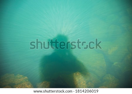 Abstract shimmering silhouette of photographer in water 