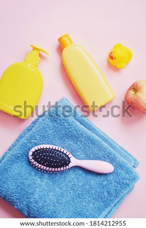 Flat lay beauty photo yellow liquid soap package, shampoo bottle, rubber duck, blue towel and hair brush