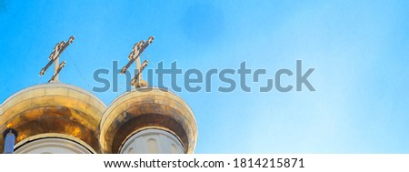 Golden domes with crosses of russian orthodox temple on blue sky background