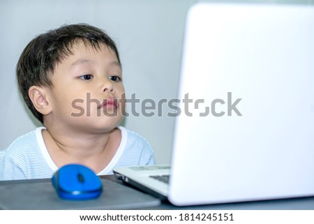 Cute little boy with white laptop in white room. Soft focus. Copy space. 