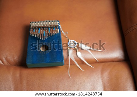 Kalimba or mbira is an African musical instrument.Traditional to the Shona people of Zimbabwe. Kalimba made from wooden board with metal and plucking with thumbs. Dream catcher key chain attached.