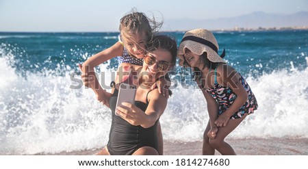 A mother with a child takes a selfie against the background of the sea and sea waves. The concept of family and recreation