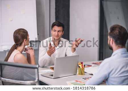 Fashion studio. Three colleagues sitting at table, discussing something