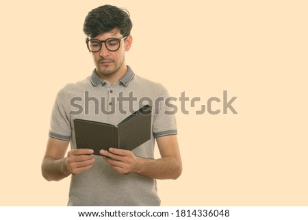 Studio shot of young Persian man reading book
