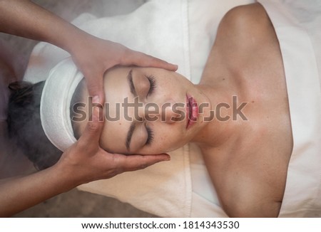 Young woman enjoying facial massage in spa salon