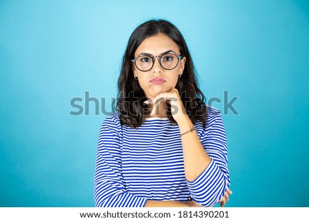 Pretty woman wearing glasses standing over insolated blue background thinking looking tired and bored with crossed arms.