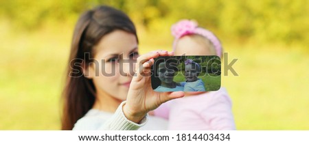 Close up mother and baby taking selfie picture by phone outdoors