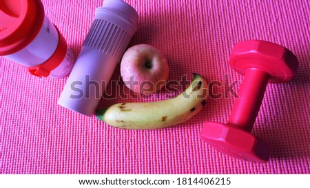 Exercise equipment and fruits placed on an orange yoga mat, the picture shows health and relaxation after exercising.
