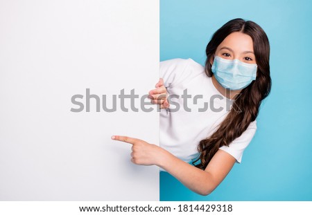 Close-up portrait cheerful cheery wavy-haired girl demonstrating empty space ad advert point finger covid outbreak news wear medical mask isolated bright shine blue color background Royalty-Free Stock Photo #1814429318
