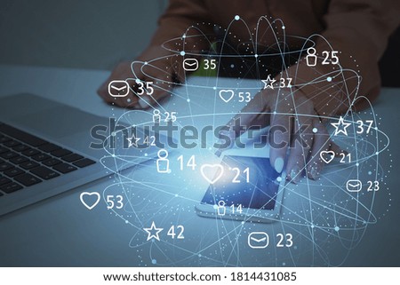 Hand of businesswoman using smartphone and laptop in blurry office with double exposure of social media interface. Toned image