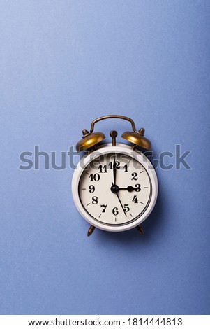 Concept of Daylight saving time. Retro clock on the blue background. Top down view with copy space