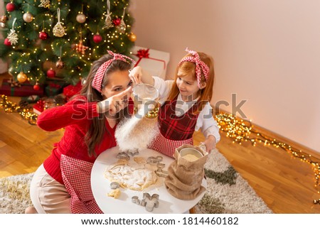 High angle view of mother and daughter kneading dough for Christmas cookies, having fun at home during winter holidays 