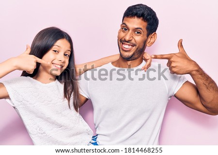 Young father and daughter wearing casual clothes smiling cheerful showing and pointing with fingers teeth and mouth. dental health concept. 