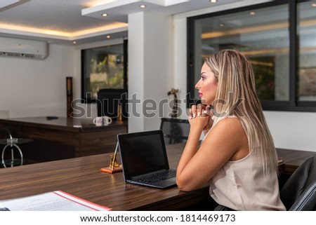 Portrait of young blonde woman using a laptop working in an office