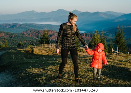 Mother and daughter enjoying time together, walking on sunset on top of foggy mountain.