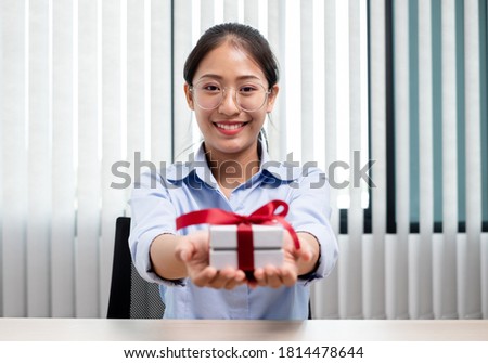 Asian woman holding a gift box Glad to be the giver of surprise with excitement, joy and smiles on the holidays, Christmas, birthdays or Valentine's Day concept.