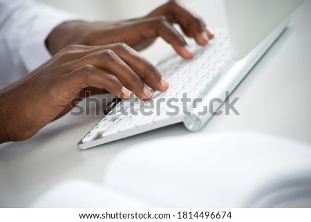 Close-up of hands of africanamerican businessman typing on a computer keyboard.