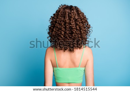 Rear back photo of young lady stand big extensive volume hairstyle nice curls sporty athletic trained spine back after exercises wear green crop top isolated blue color background Royalty-Free Stock Photo #1814515544