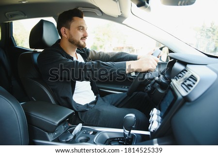 Test drive for auto. Pleasant overjoyed handsome boy holding steering wheel and driving his car while expressing gladness