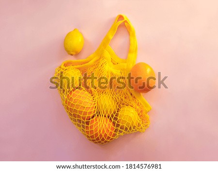 Mesh shopping bag with lemons on pink canvas background