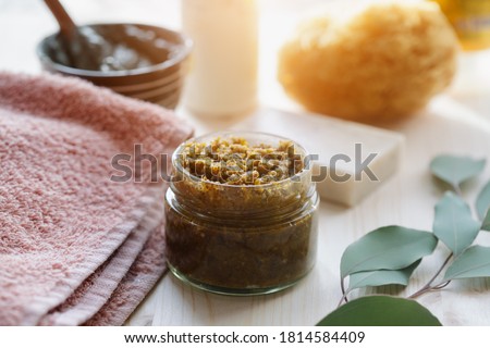 spa cosmetic products, milk soap, handmade sugar coffee scrub with coconut oil in glass jar and towel on wooden table Royalty-Free Stock Photo #1814584409