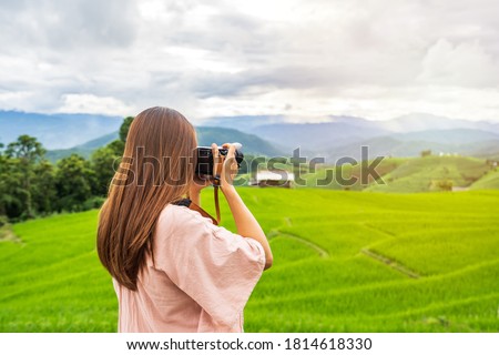 Young woman traveler on vacation taking a picture at beautiful green rice terraces field in Pa Pong Pieng, Chiangmai Thailand