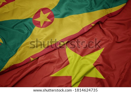 waving colorful flag of vietnam and national flag of grenada. macro