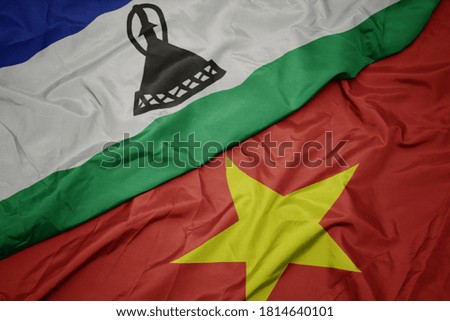waving colorful flag of vietnam and national flag of lesotho. macro