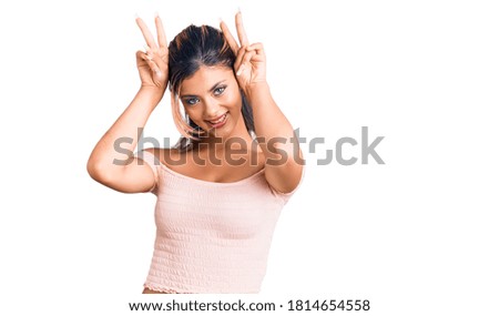 Young beautiful woman wearing casual clothes posing funny and crazy with fingers on head as bunny ears, smiling cheerful 