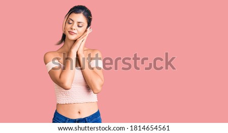 Young beautiful woman wearing casual clothes sleeping tired dreaming and posing with hands together while smiling with closed eyes. 