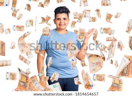 Little boy kid wearing sports workout clothes smiling cheerful presenting and pointing with palm of hand looking at the camera.