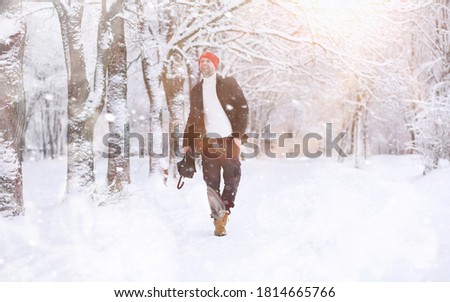 A man on a walk in the park. Young man with an umbrella under the winter snowfall.