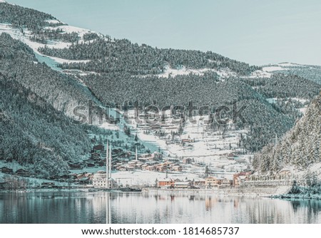 Uzungol scenic lake  panorama in inter with traditional turkish mosque and living houses and forest in the background.Winter travel holidays in Turkey. 2020
