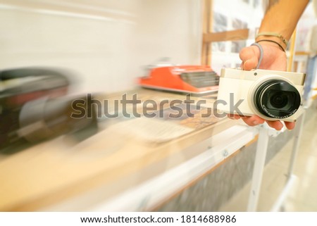 Person hand holds white small digital camera next to vintage previous generation analog camera. Intentional blur background image. Concept of evolution of cameras.