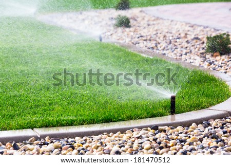 Automatic sprinklers watering grass Royalty-Free Stock Photo #181470512