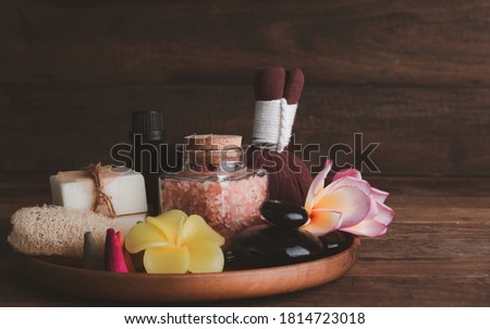 Spa products with  organic soap,luffa scrub,compress ball,pink salt,black stones, and beautiful plumerai flower on wooden tray  over dark wood background  Royalty-Free Stock Photo #1814723018
