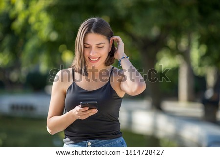 Young beautiful Turkish woman is checking mobile phone while smiling