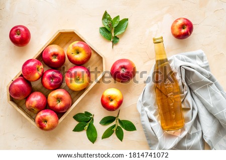 Apple cider vinegar in glass bottle and wooden tray with red apples Royalty-Free Stock Photo #1814741072