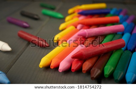 Colored wax crayons used by children in school on gray wood