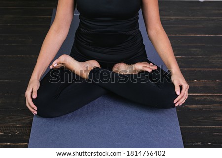 Healthy habits the concept of a calm mind. Hands close-up view. Athletic woman practicing yoga, doing Padmasana exercise, half-Lotus pose, training in black leggings, indoor yoga Studio.