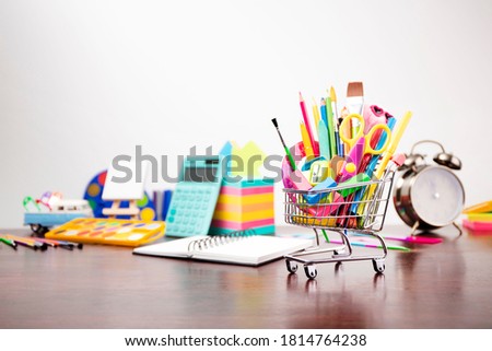 Mini shopping cart full of colorful school supplies. Education concept.