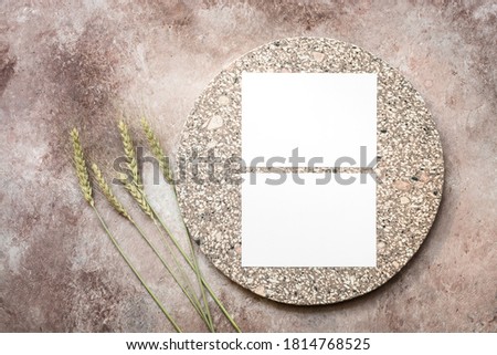 Blank business cards mockup on a granite plate and ears of wheat. Beige brown textured background. Company corporate identity template. Top view, flat lay.