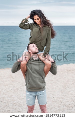 Young couple enjoying and having fun at the beach in matching outfits. Sweet and romantic boyfriend and girlfriend pre wedding photoshoot. Valentines day pictures