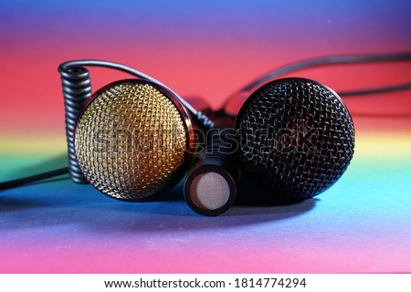 A closeup shot of headphone and microphones on a colorful background