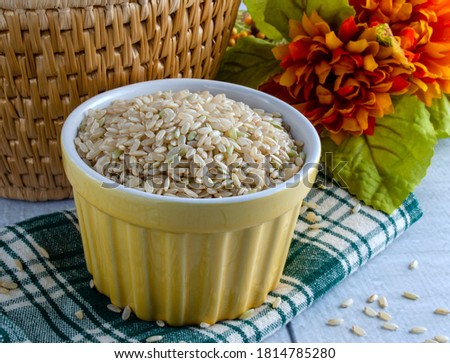 Uncooked brown rice in yellow bowl.  Overhead view with horizontal composition.