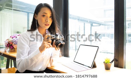 Portrait of female photo grapher checking photo on digital camera while working in office.